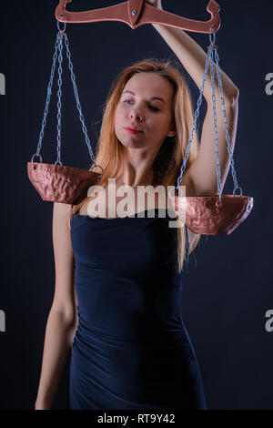 Attractive beautiful girl with Libra in hand as a symbol of the air zodiac sign or Goddess Themis Stock Photo