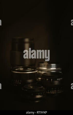 A collection of vintage lenses with against a black background with focus point on the lower aperture numbers. Stock Photo