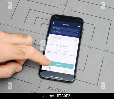 PARIS, FRANCE - NOV 9, 2017: Male hand touch selecting New Apple iPhone x 10 smartphone after unboxing and testing by installing the Trainline booking ticket searching place from Paris to London app application software Stock Photo
