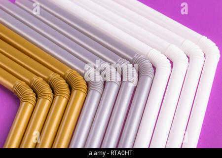 Colorful plastic drinking straws tightly pressed against each other on a purple table, close-up as background. The concept of a holiday and a cheerful Stock Photo