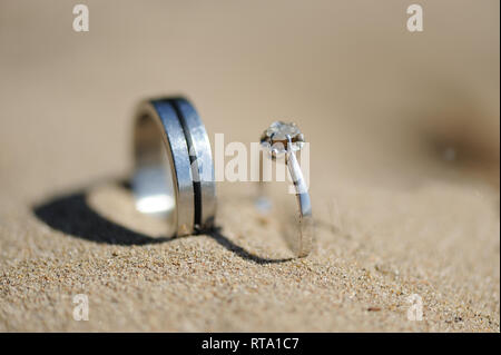 silver rings with diamonds inserted in sand Stock Photo