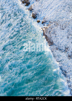 Aerial Drone shot showing the ocean and wave breaks against the reef Stock Photo