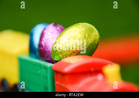 Closeup of vivid, colour easter eggs load for transport on plastic train locamotive. Easter holiday theme for child of Easter Eggs, play and travel. Stock Photo