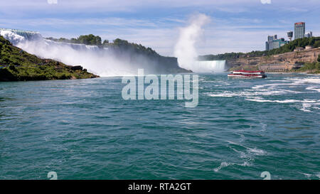 NIAGARA FALLS, ONTARIO, CANADA - JUNE 25, 2018: View of Hornblower tour boat, navigating close to the American Fall and the shore of the canadian side Stock Photo