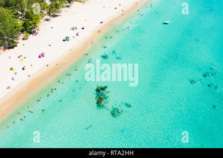 View from above, aerial view of a beautiful tropical beach with white sand, turquoise clear water and people sunbathing, Surin beach, Phuket, Thailand Stock Photo