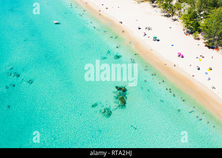 View from above, aerial view of a beautiful tropical beach with white sand, turquoise clear water and people sunbathing, Surin beach, Phuket, Thailand Stock Photo