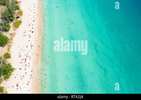 View from above, aerial view of a beautiful tropical beach with white sand, turquoise clear water and people sunbathing, Surin beach, Phuket, Thailand Stock Photo