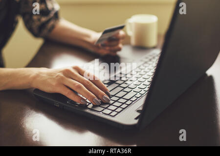 Young woman holding credit card with and typing on laptop Stock Photo