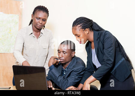 Three business partners working on a laptop in the office and sharing knowledge. Stock Photo