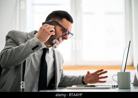 Furious businessman is talking on phone. Stock Photo