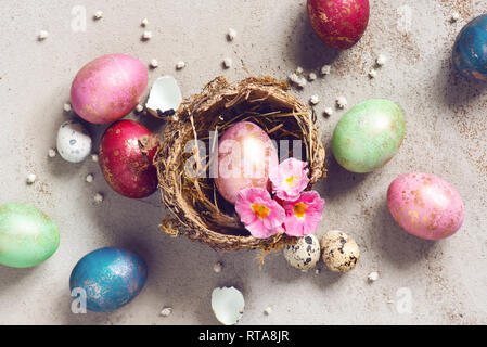 Colorful Easter eggs with golden spots in the natural small nest, top view Stock Photo