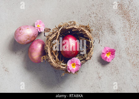 Three pink Easter eggs with golden spots in the natural small nest, top view Stock Photo