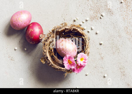 Three pink Easter eggs with golden spots in the natural small nest, top view Stock Photo