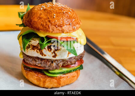 Close up tall tasty burger with cheese served on tray Stock Photo