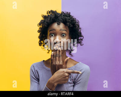 Secret, gossip concept. Young woman calling for silence. woman isolated on trendy color studio background. Young emotional african woman. Human emotions, facial expression concept.