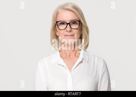 Older businesswoman in glasses looking at camera isolated on background Stock Photo