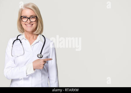 Smiling doctor with stethoscope pointing at copyspace isolated on background Stock Photo