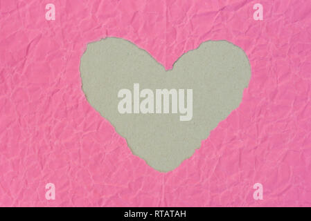 heart shape  hole on piece on pink color paper Stock Photo