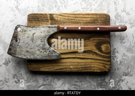 Old rustic axe for meat on a wooden board on grunge background. Food photography Stock Photo