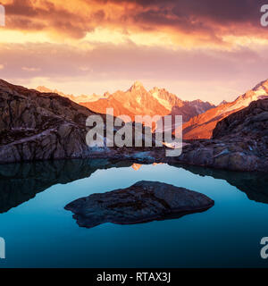 Alpine mountain landscape with lake and peaks covered by snow on sunset time