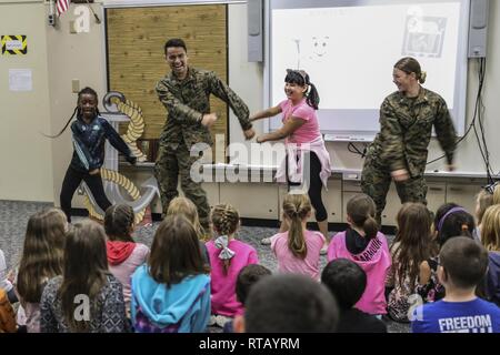 Navy Lt. Kristopher Zamora, center left, and Lt. Kathryn Harrington, right, do the “floss” dance with students from Kinser Elementary School Feb. 5, 2019 on Camp Kinser, Okinawa, Japan. Sailors from Naval clinics in Okinawa held a presentation to promote oral health awareness during National Children’s Dental Health Month. Zamora, a general dentist with Branch Dental Clinic Hansen, 3rd Dental Bn., 3rd Marine Logistics Group, is a native of Caldwell, Idaho. Harrington, a general dentist with Branch Dental Clinic Futenma, 3rd Dental Bn., 3rd MLG, is a native of Cleveland, Ohio. Stock Photo