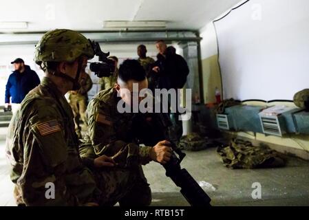 ŚWIĘTOSZÓW, Poland (Feb. 5, 2019) - Army Pfc. Cody Patrick, a Bradley Mechanic and Staff Sgt. Nicholas Rolison, a Mortarman, both with the 1st Squadron, 4th U.S. Cavalry Regiment, out of Fort Riley, Kan., train on the M240-B Machine Gun while Vincent “B.J.” Lawrence, the Commander-in-Chief of the Veterans of Foreign Wars of the U.S., observes. As commander of the VFW, Lawrence personally visited the soldiers of the 1-4 Cavalry while mobilized in an effort to better understand the training environment and living conditions of the troops stationed overseas in support of Operation Atlantic Resolv Stock Photo