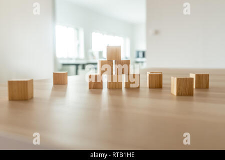 Wooden cubes positioned in a pyramid shape on office desk in a conceptual image. Stock Photo