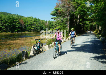 Two women riding their bikes on the Eagle Lake loop carriage road, Acadia National Park, Maine, USA. Stock Photo