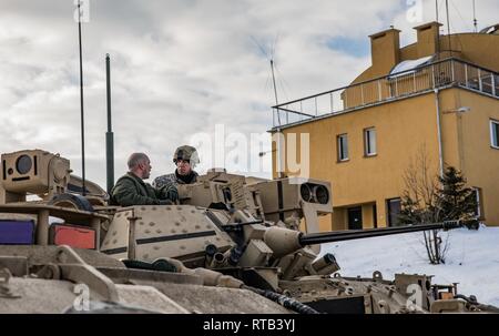 ŚWIĘTOSZÓW, Poland (Feb. 6, 2019) - Staff Sgt. Daniel Agriesti, a Cavalry Scout from the 1st Squadron, 4th U.S. Cavalry Regiment out of Fort Riley, Kan., explains the capabilities of the M2 Bradley fighting vehicle to Vincent “B.J.” Lawrence, the Commander-in-Chief of the Veterans of Foreign Wars of the U.S., prior to a live-fire exercise at a firing range near Świętoszów. As commander of the VFW, Lawrence personally visited the soldiers of the 1-4 Cavalry while mobilized in an effort to better understand the training environment and living conditions of the troops stationed overseas in suppor Stock Photo