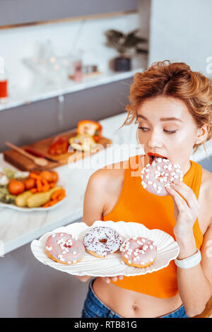 Beautiful young woman holding a plate with donuts Stock Photo