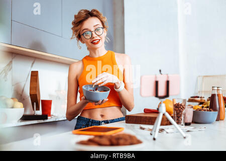 Nice cheerful woman holding a bowl with porridge