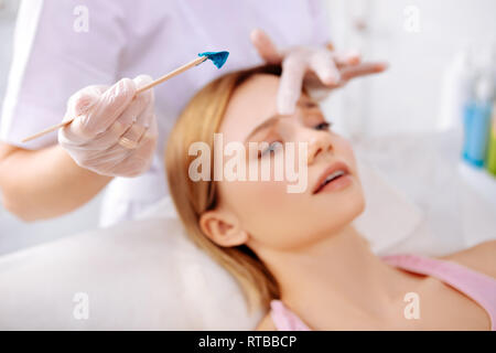 Blonde woman feeling some pain while having depilation of face Stock Photo