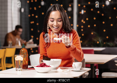 Pleasant long-haired woman tasting soup with pleasure. Stock Photo