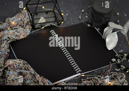 Opened notebook with black sheets on dark background. Top view. Stock Photo