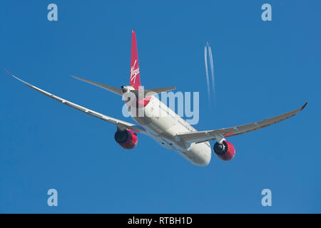 A Virgin Atlantic Boeing 787 Dreamliner Climbing Into Clear Blue Skies, A High Flying Boeing 747 Contrailing Overhead. Stock Photo