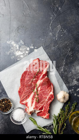 Fresh beef steak on black background with herbs and spices. Ready for cooking. Top view, down edge with copy space Stock Photo