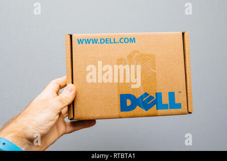 PARIS, FRANCE - NOV 6, 2017: IT service man holding against gray background cardboard box with DELL computer logo spare part inside for his IT department Stock Photo