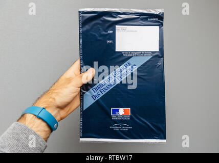 PARIS, FRANCE - OCT 4, 2017: Man holding against gray background envelope containing Taxe d'habitation (rates, property tax) which is sent once per year to very household owner or people who rent a house apartment Stock Photo