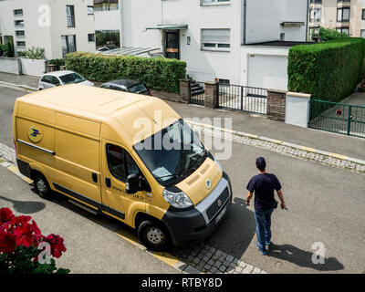 PARIS, FRANCE - JUN 23, 2017: Courier walking toward La Poste yellow delivery van for the delivery on time package parcel - aerial view Stock Photo