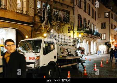STRASBOURG, FRANCE - NOV 21, 2017: Decorating a shop facade for Christmas by using a truck with hydraulic ladder in central street with people at night  Stock Photo
