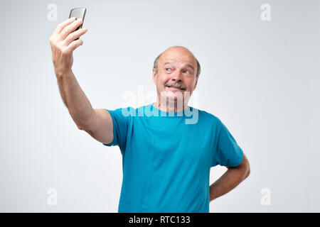Excited senior man using mobile phone make selfie. Positive facial emotion. Stock Photo