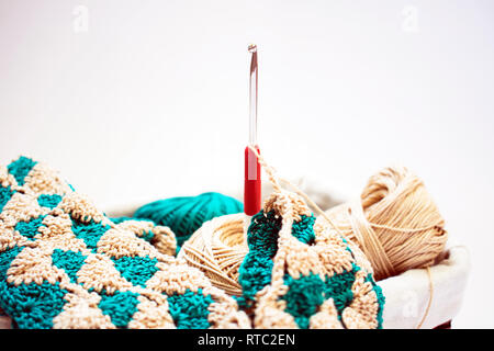 Beige and green threads, knitting and crochet hook isolated on a white background. Stock Photo