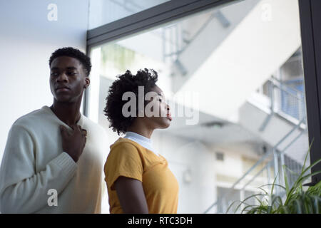 A young attractive black couple looking serious in a simple white room, modern fashionable photoshoot.