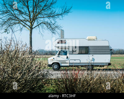 Dortmund, Germany - Feb 24, 2018: Side view of vintage RV camper van driving toward vacation destination on a warm clear sunny morning in German autobahn Stock Photo