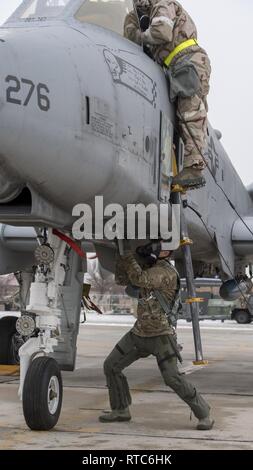 A pilot from the 190th Fighter Squadron preflights an A-10 Thunderbolt II while a crew chief from the 124th Aircraft Maintenance Squadron prepares the aircraft during a unit training assembly at Gowen Field, Boise, Idaho on Feb. 9, 2019. The pilots and crew chiefs work closely together to ensure a successful sortie can occur. Stock Photo