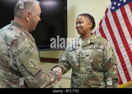 Sgt. Shantel Jones, 184th Sustainment Command, is presented a coin for excellence by Command Sgt. Maj. Jason Little, 184th senior advisor, after her promotion ceremony at Camp Arifjan, Kuwait, Feb. 10, 2019. Stock Photo