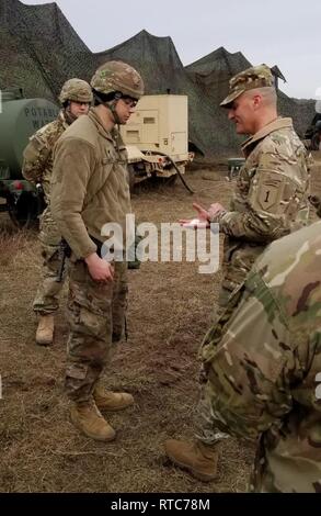 Col. Patrick Michaelis, the commander of the Mission Command Element, 1st Infantry Division, out of Fort Riley, Kansas, gives a coin to Spc. Caleb Shuler, a multi transmission systems operator maintainer with the MCE, during a command post exercise in the Alexander Training Area, in Biedursko, Poland, Feb. 10.    The purpose of the field exercise is to improve readiness, perform command post functions, and to stress the ability to move the MCE quickly when told.     The training includes route planning, sustainment operations, maintenance readiness, and communications set up that will enable c Stock Photo