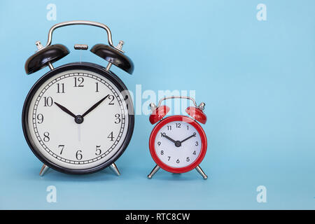 two red and black retro alarm clocks on a blue background with free space for text Stock Photo