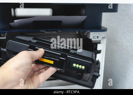 technician office worker fixing photocopy machine with replacement toner cartridge. refilling cartridge with toner for printing documents. Stock Photo