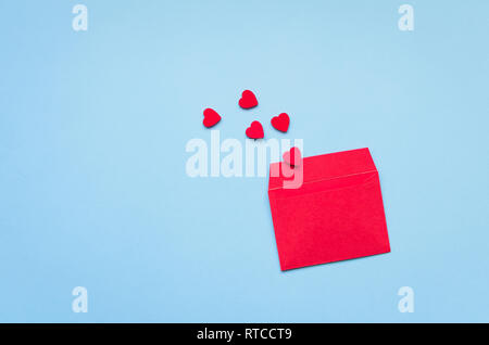 Opened red envelope and many felt hearts on blue background with place for text. Love letter mail correspondence relationship. Valentines day concept. Stock Photo